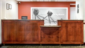 Mostrador de recepción de hotel con un cuadro enmarcado de una noria y la palabra 'explore'.