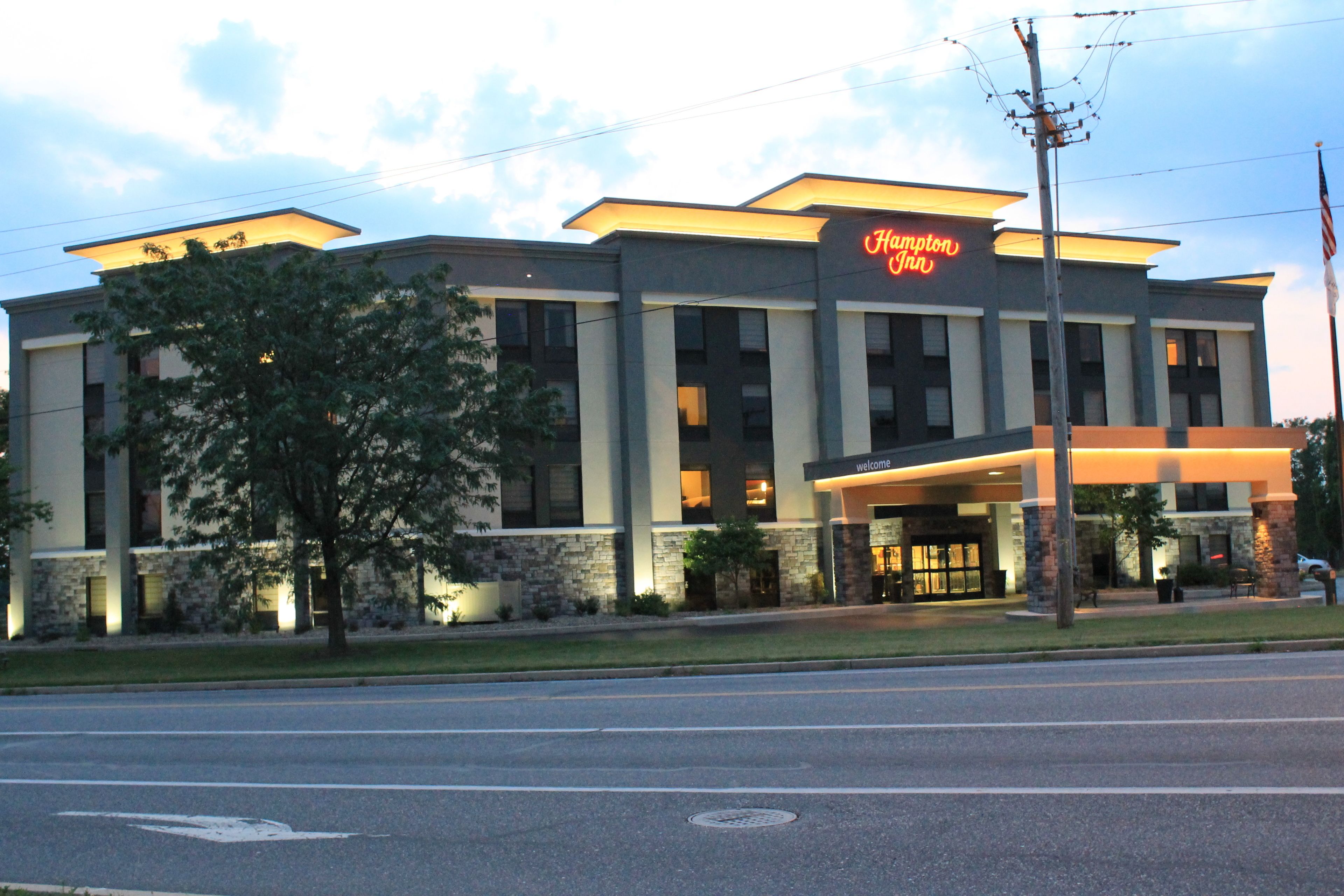 A Hampton Inn hotel with a modern design, featuring a prominent entrance and a well-lit facade.