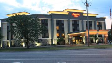 A Hampton Inn hotel with a modern design, featuring a prominent entrance and a well-lit facade.