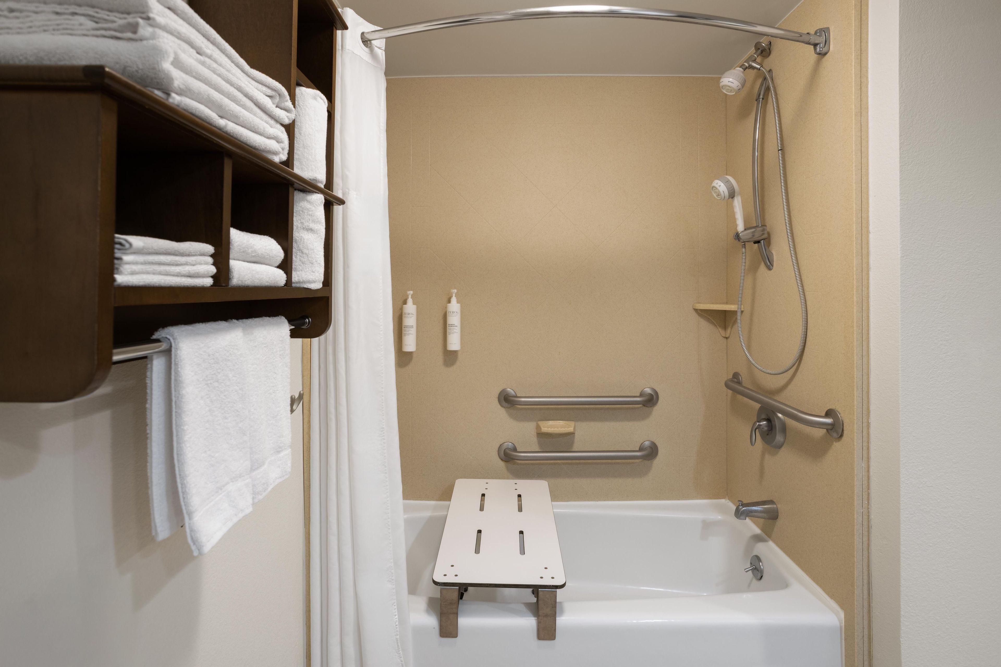 Une salle de bain avec une douche, une baignoire et une étagère où sont rangées les serviettes.