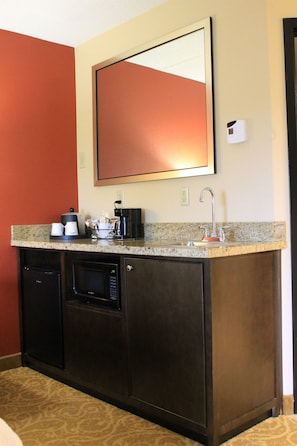 Un bagno di hotel piccolo con lavandino, specchio, macchina del caffè e forno a microonde.