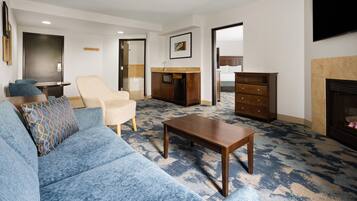 Una sala de estar con un sofá azul, una mesa de centro de madera, un sillón beige y un aparador.