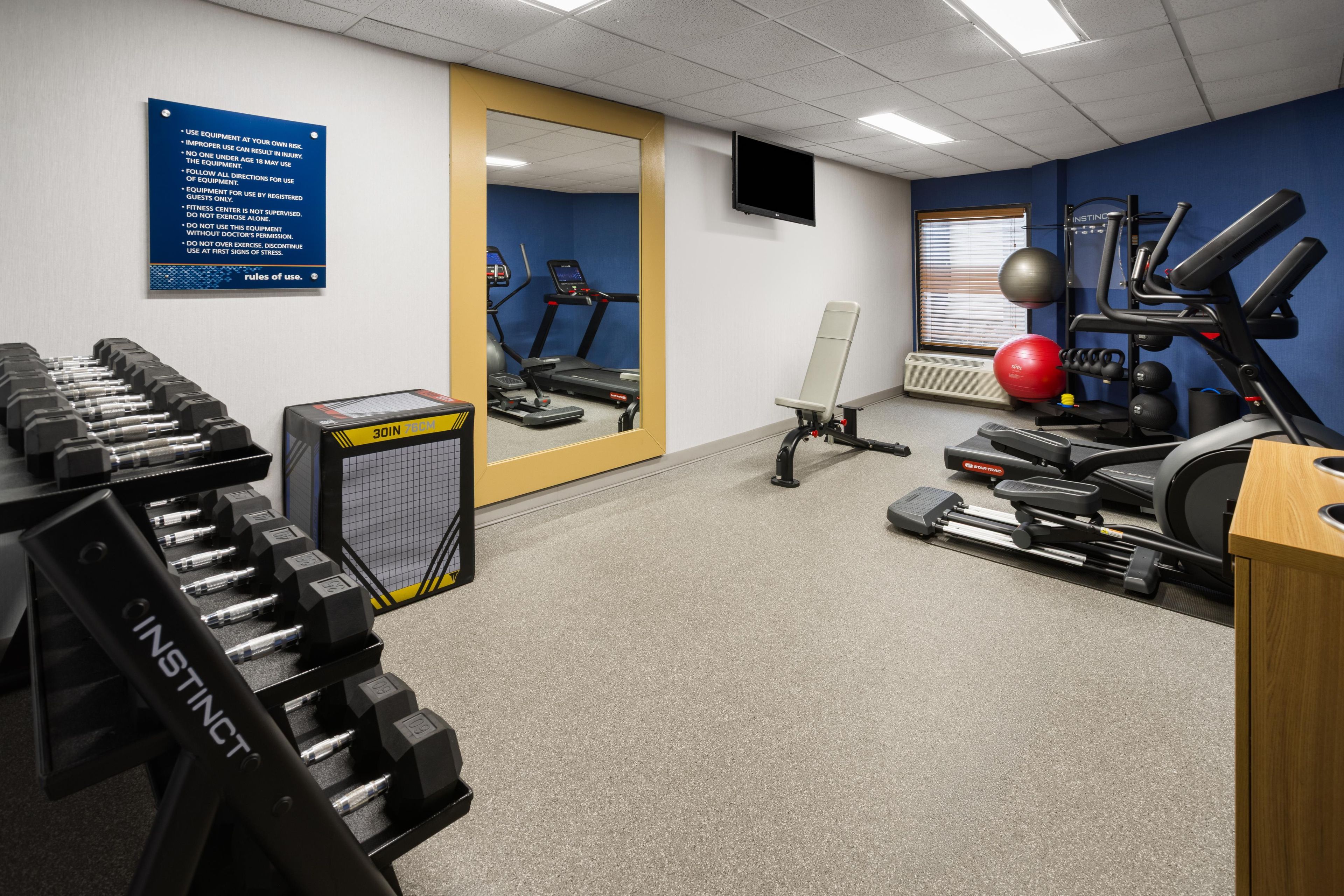 A gym with exercise equipment, a treadmill, and a mirror.