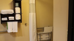 A bathroom with a shower, a towel rack, and a small shelf with folded towels.