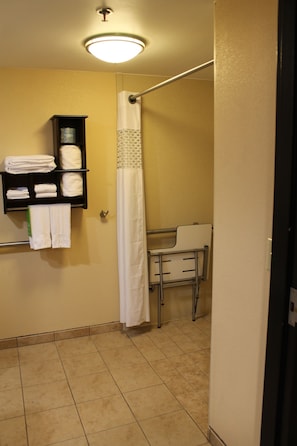 Un bagno con doccia, un portasciugamani e un piccolo ripiano con asciugamani piegati.