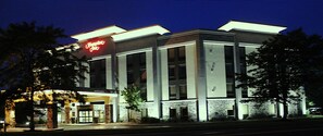 Hotel Hampton Inn dal design moderno, con un cartello rosso ben visibile, ampie finestre e un ingresso accogliente.