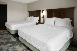 Una habitación de hotel con dos camas, una mesita de noche y una lámpara.