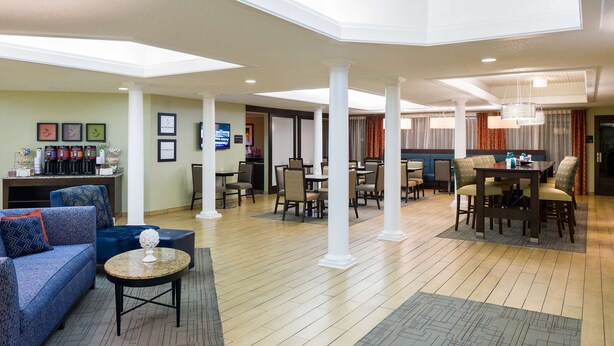 En rummelig hotellobby med højt til loftet, flere siddeområder og en bar.