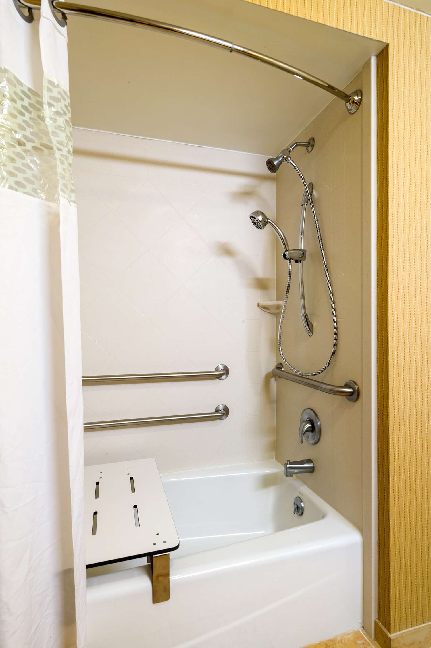 A bathroom with a bathtub, a shower, and a grab bar.