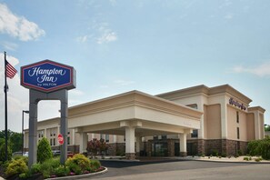 A Hampton Inn by Hilton with a stop sign, a welcoming entrance, and a landscaped area.