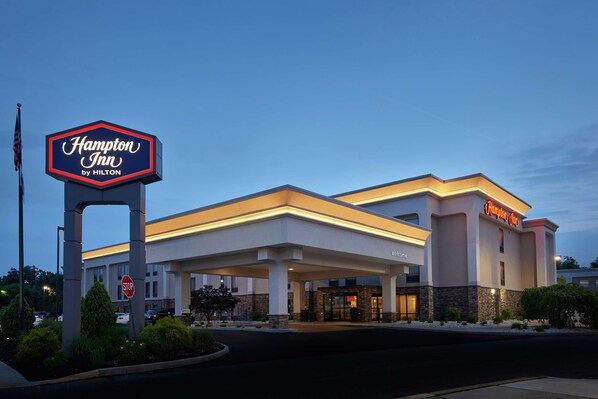 A Hampton Inn by Hilton hotel with a prominent sign, a welcoming entrance, and a well-lit facade.