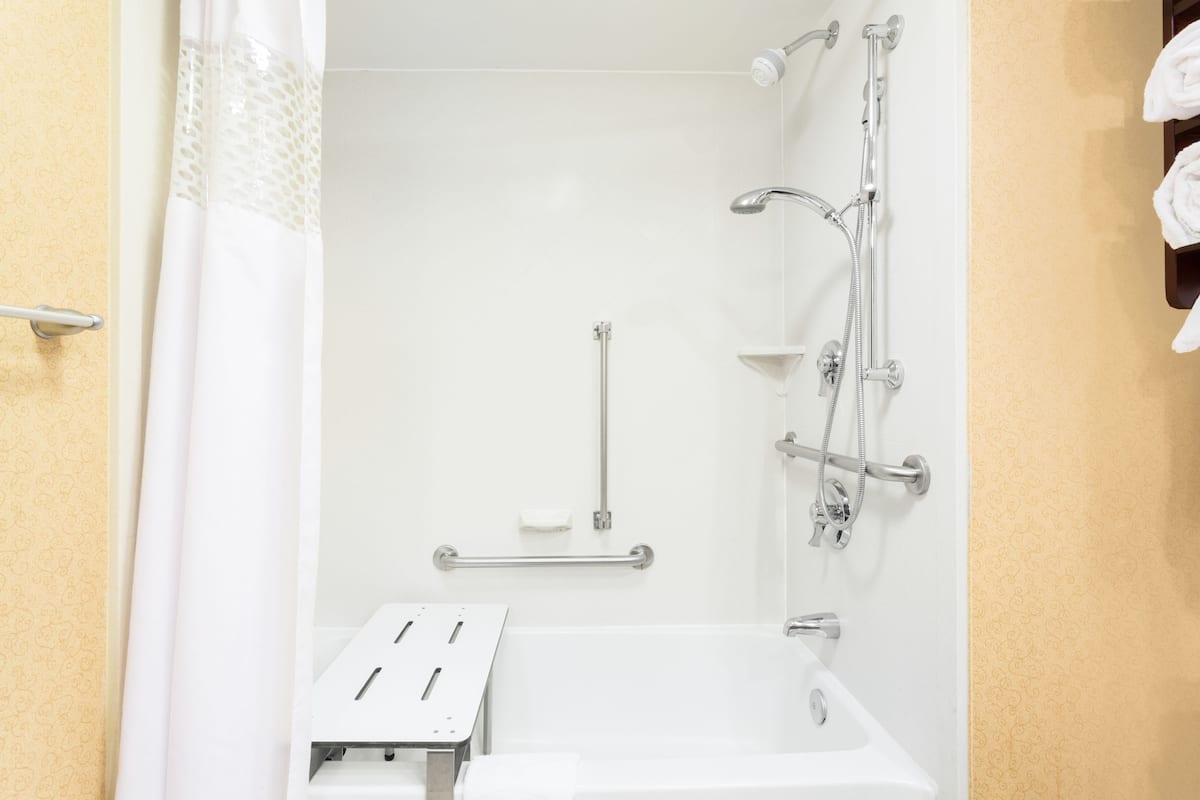 A bathroom with a shower, a sink, and a grab bar.