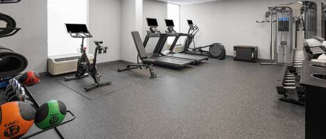 Un gimnasio con cintas de correr, bicicletas estáticas y máquinas de pesas.