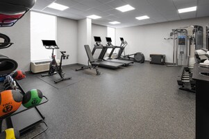 Un gimnasio con cintas de correr, bicicletas estáticas y máquinas de pesas.