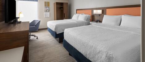 A hotel room with two beds, a desk, a TV, and a chair.