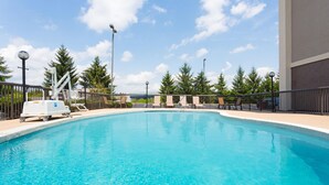 A swimming pool with lounge chairs and a lifeguard stand.