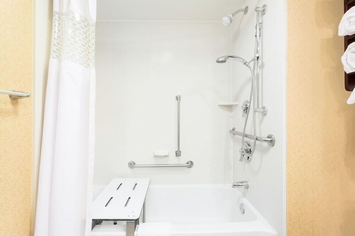 Un baño con ducha, lavamanos y un perchero para toallas.