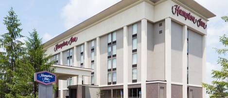 Um hotel Hampton Inn com fachada moderna, grandes janelas e entrada acolhedora.