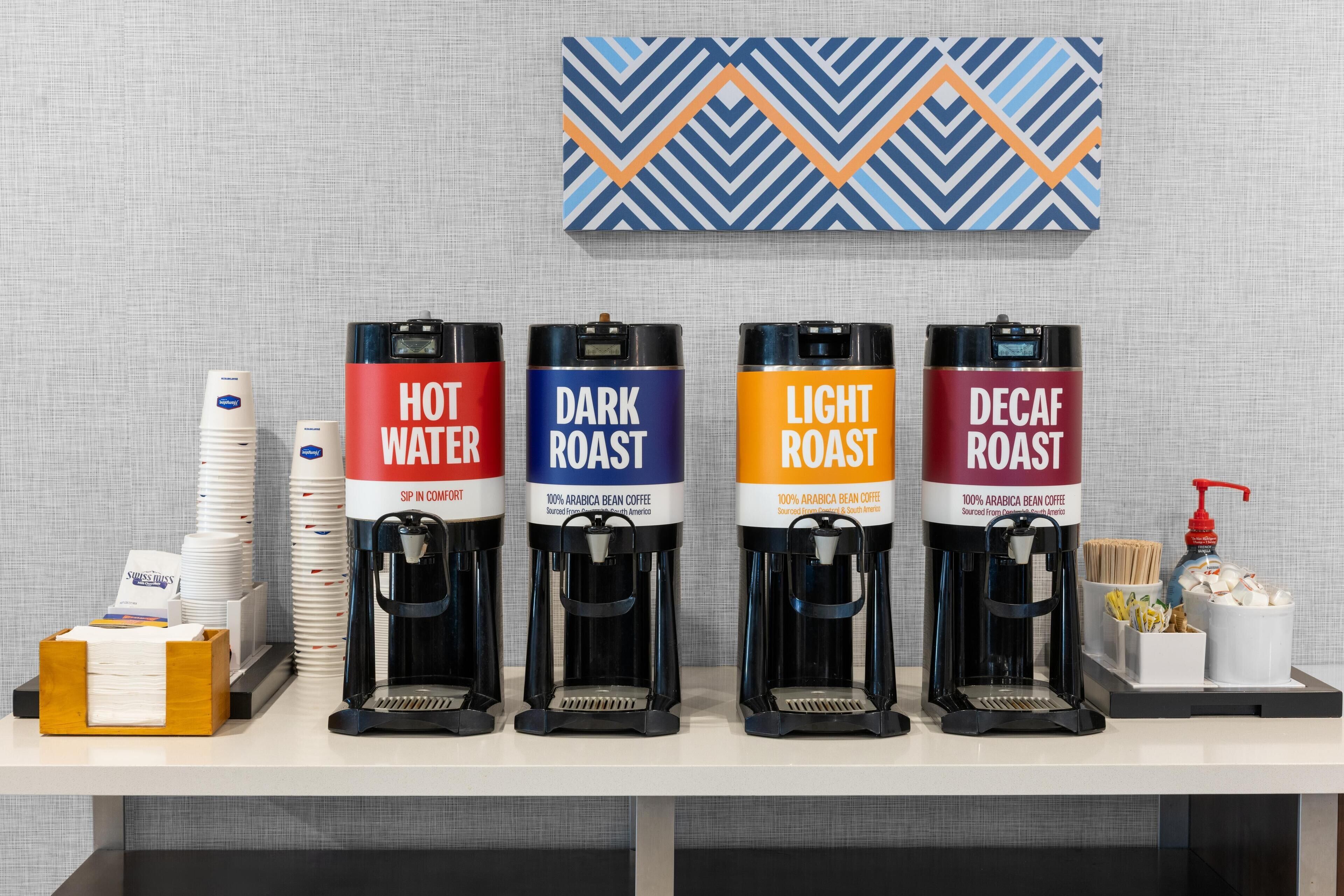 Cuatro dispensadores de café con las etiquetas 'AGUA CALIENTE', 'TORREFACHO OSCURO', 'TORREFACHO CLARO' y 'DESCAFEINADO'.