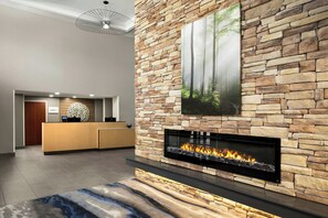 A lobby with a stone wall, a fireplace, a reception desk, and a ceiling light fixture.