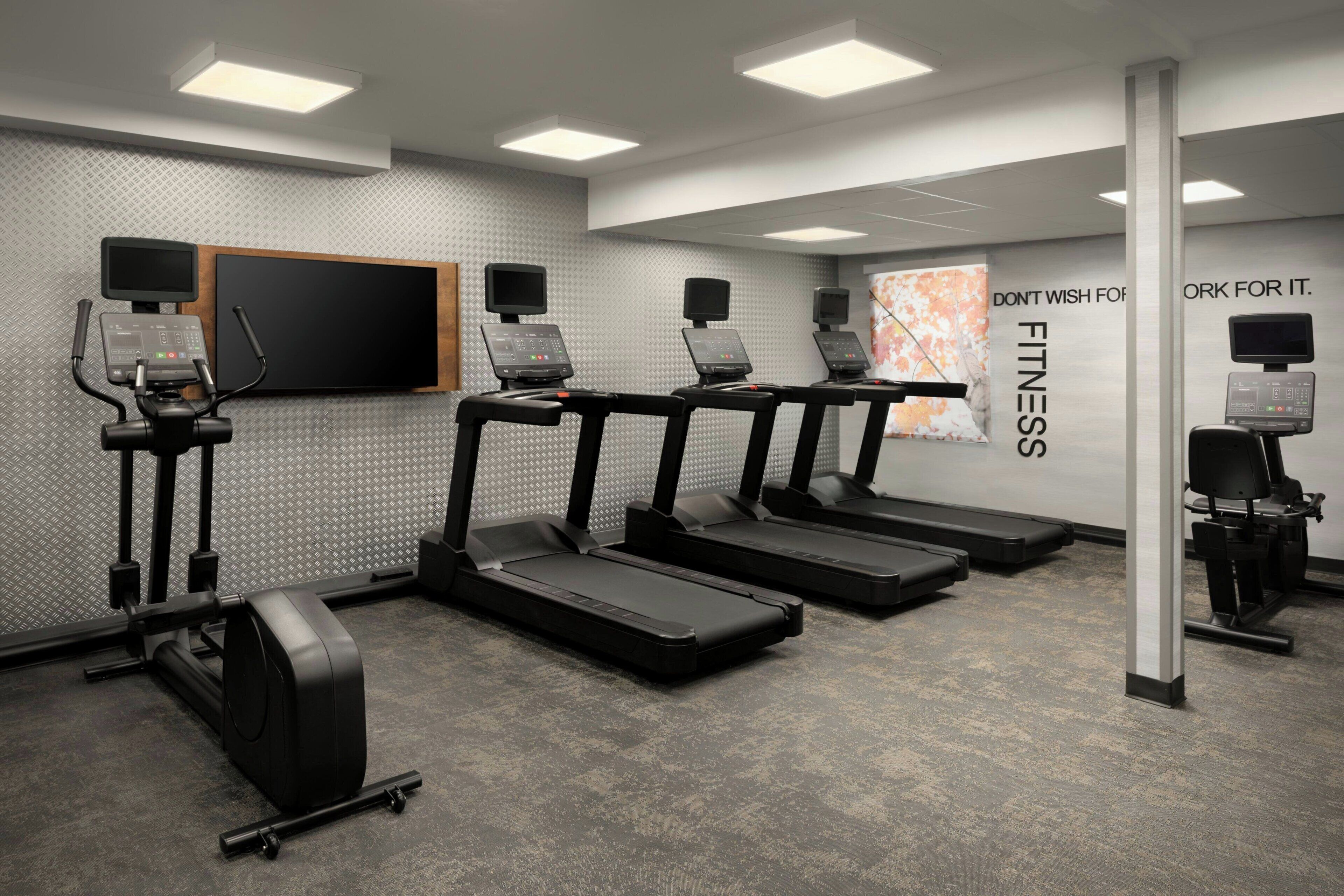 Un gimnasio moderno con cintas de correr, elípticas y bicicletas estáticas.