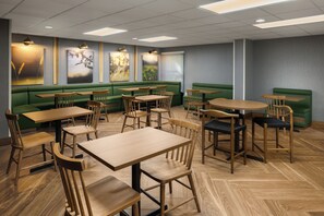 A restaurant with green booths, wooden tables, and chairs.