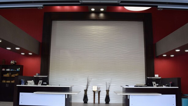 A reception area with two reception desks, a red wall, and a textured wall behind the desks. - Best Western Plus Hardeeville Inn & Suites (Hardeeville)