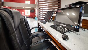 A workspace with two laptops and a desktop computer, a black leather chair, and a white countertop. - Best Western Plus Hardeeville Inn & Suites (Hardeeville)