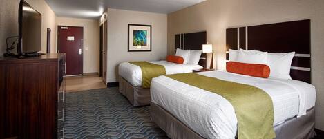 A hotel room with two beds, a desk, a TV, and a painting on the wall.