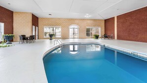 An indoor swimming pool with a brick wall, a table with chairs, and a door.