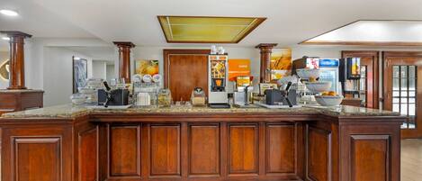 A large wooden kitchen island with a built-in coffee station, a microwave, and a refrigerator.