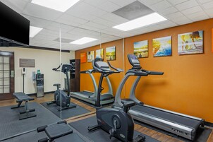 Un gimnasio con cintas de correr, elípticas y bancos de pesas.