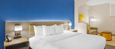 Habitación de hotel con una cama grande, mesitas de noche, una lámpara, una silla y una pequeña mesa.