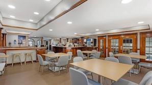 A spacious dining area with multiple tables and chairs, a counter with a beverage station, and a kitchen area in the background. - Comfort Suites Sumter near Shaw AFB (Sumter)