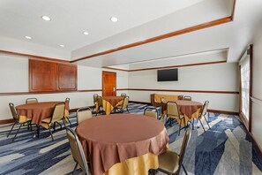 A conference room with round tables, chairs, a flat-screen TV, and a large window. - Comfort Suites Sumter near Shaw AFB (Sumter)