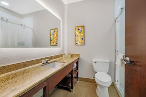 A bathroom with a granite countertop, a white toilet, and a glass shower enclosure. - Comfort Suites Sumter near Shaw AFB (Sumter)