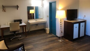 Habitación de hotel con escritorio, silla, televisor, lámpara y puerta azul.
