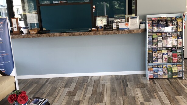 Zona de recepción con mostrador, un reloj y una exhibición de revistas.
