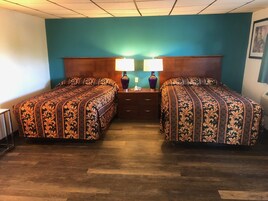 Una habitación de hotel con dos camas, un cabecero de madera, una mesita de noche con lámparas y un cuadro en la pared.