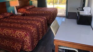 Habitación de hotel con dos camas, un escritorio, una silla, un televisor y vistas al exterior.