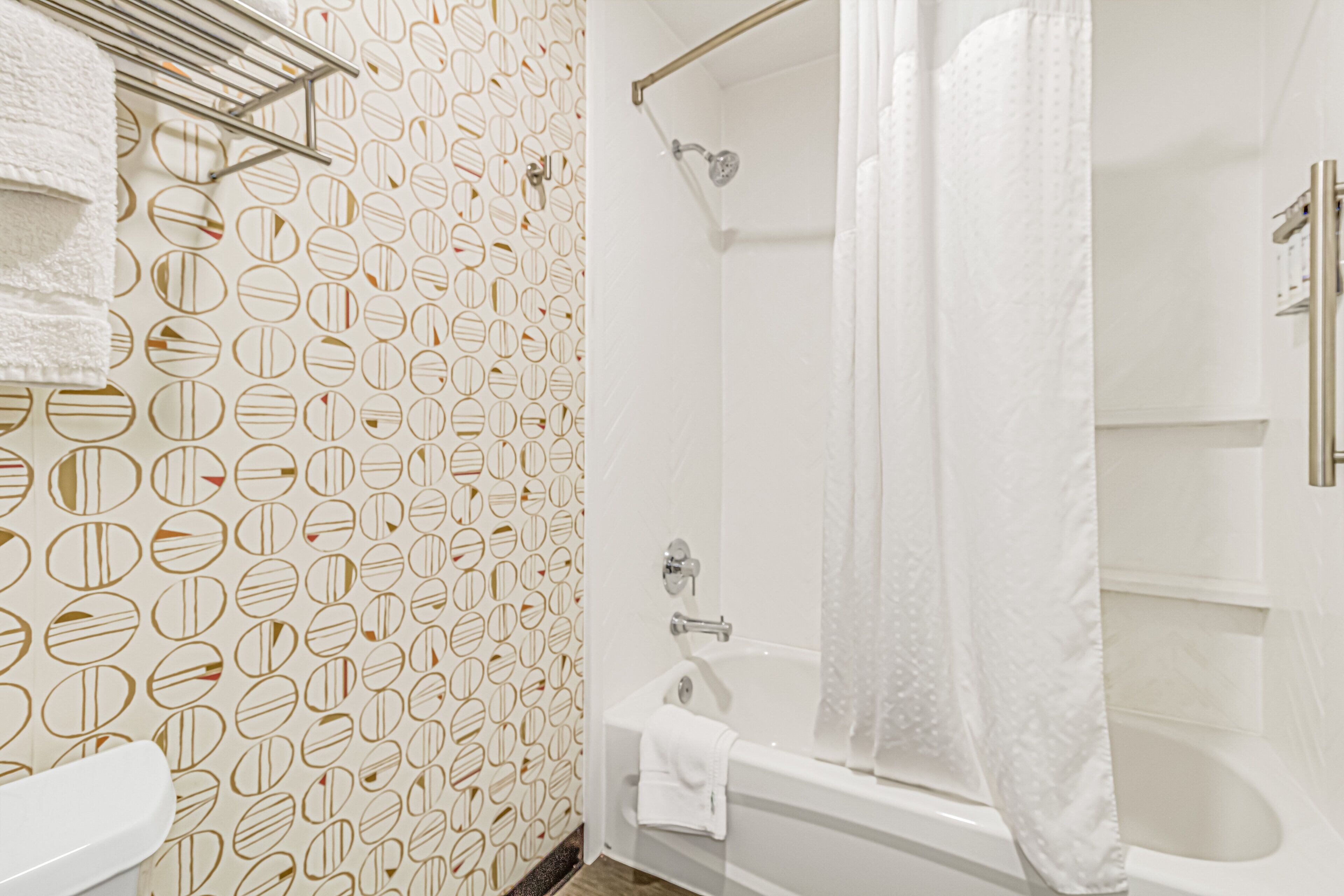 A bathroom with a patterned wall, a bathtub, and a shower area.