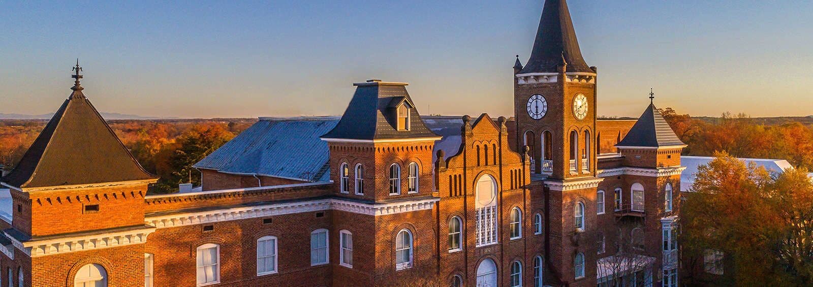 A large brick building with multiple towers and a clock tower, featuring arched windows and a prominent steeple.