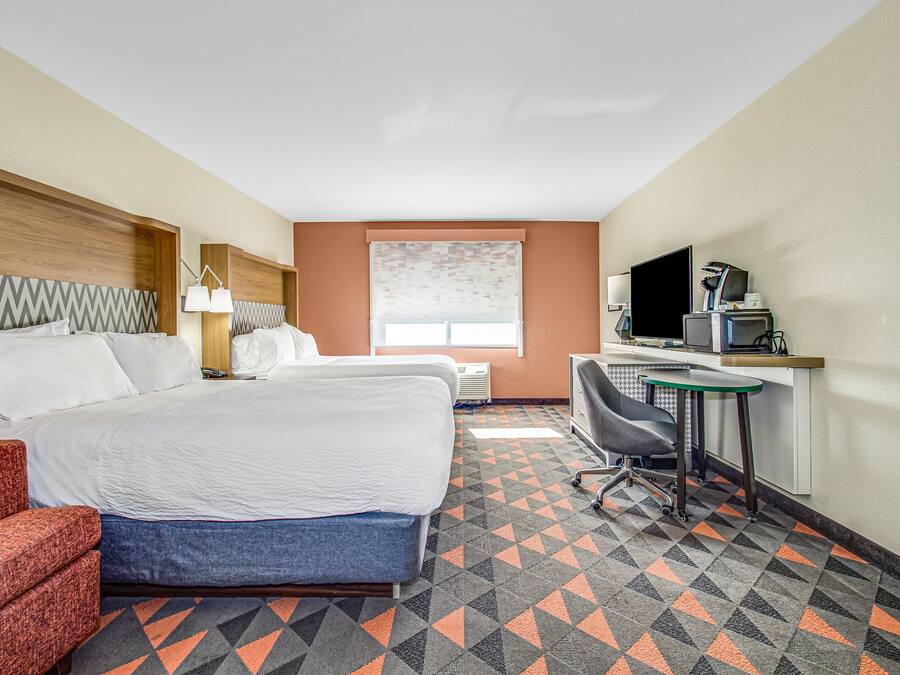 A hotel room with a bed, desk, chair, and a TV.