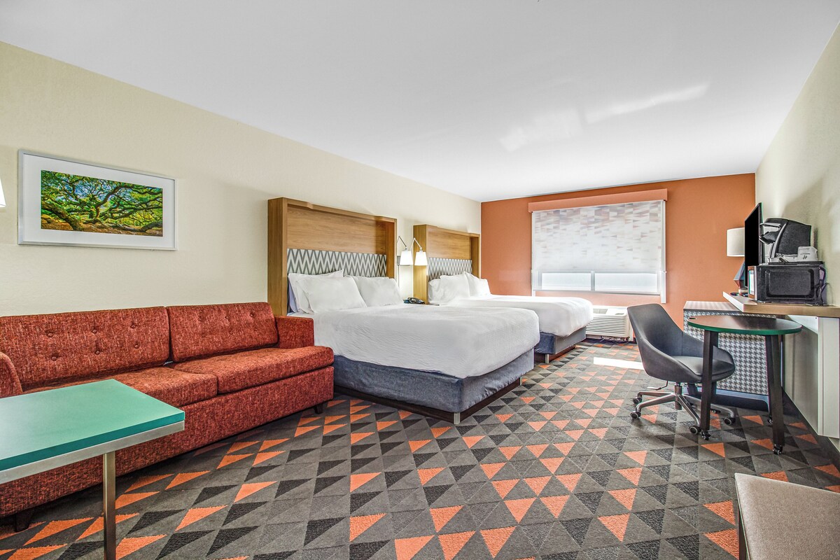 Ein Hotelzimmer mit Bett, Sofa, Schreibtisch und Stuhl.