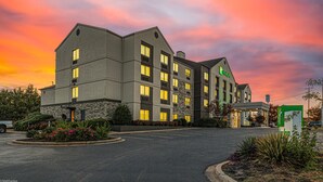 Un hôtel à plusieurs étages, doté d’une façade en pierre et de nombreuses fenêtres, comprenant un parking et des espaces paysagers.
