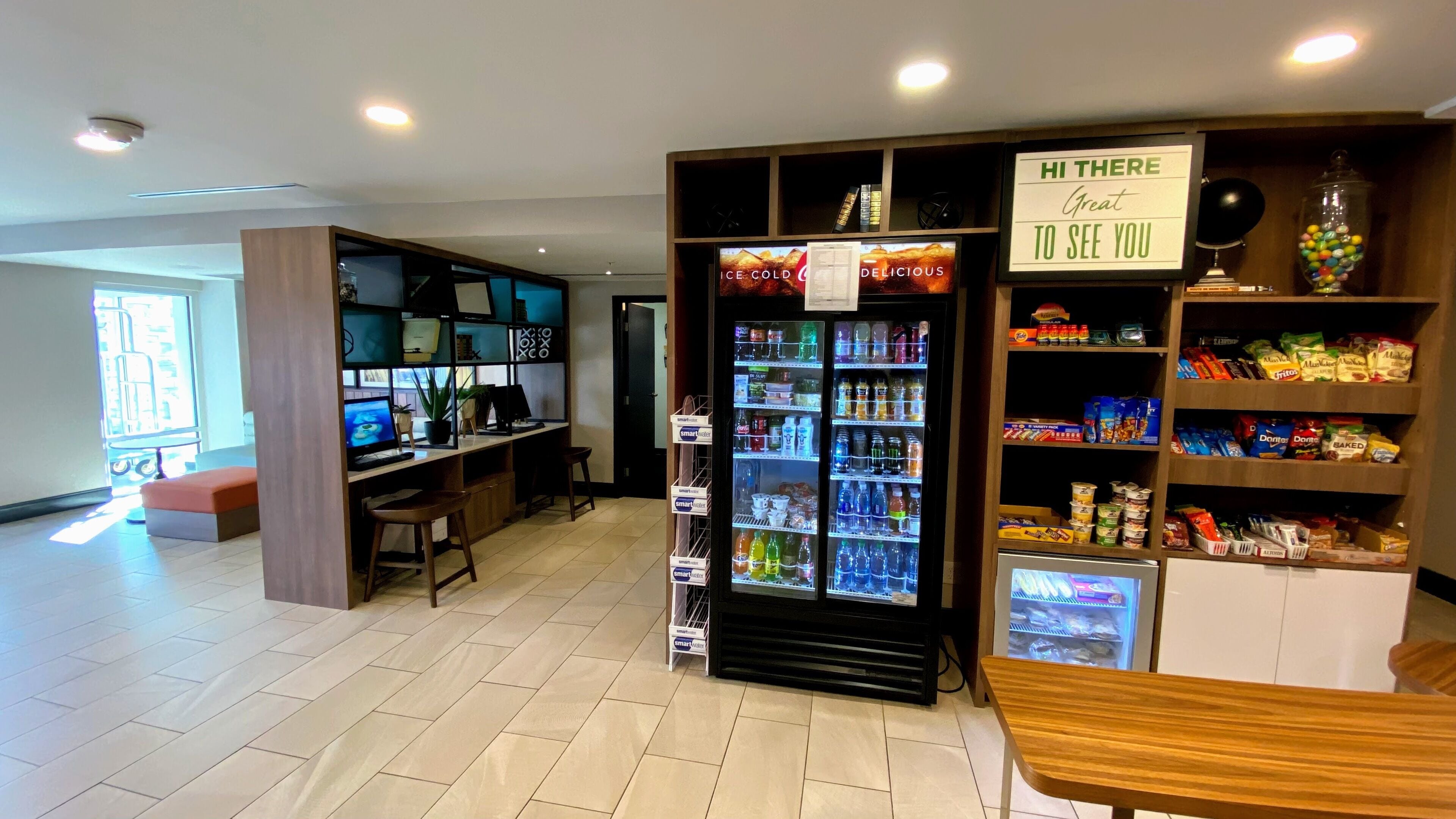 A modern kitchenette with a refrigerator, a coffee machine, and a small seating area.
