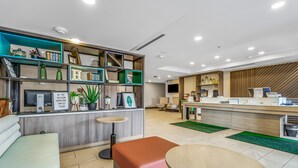Un espace d’accueil moderne comprenant un comptoir, des sièges et une bibliothèque contenant divers objets.