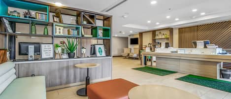 Ett modernt receptionsområde med en receptionsdisk, sittplatser och en bokhylla med diverse föremål.