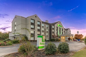Un hotel Holiday Inn Express con un diseño moderno, que cuenta con un letrero grande, varias ventanas y un estacionamiento.