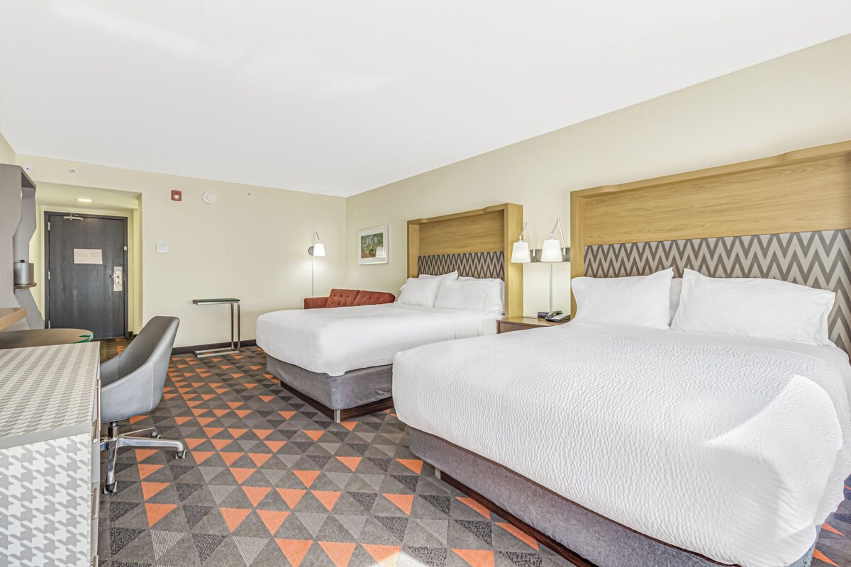 Ein Hotelzimmer mit zwei Betten, einem Schreibtisch und einem Stuhl.